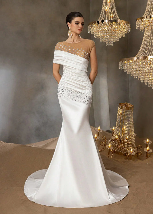 White wedding dress with intricate detailing in a decorated room with chandeliers.